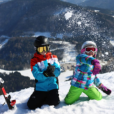 Kinder in Skianzug werfen Schneebälle